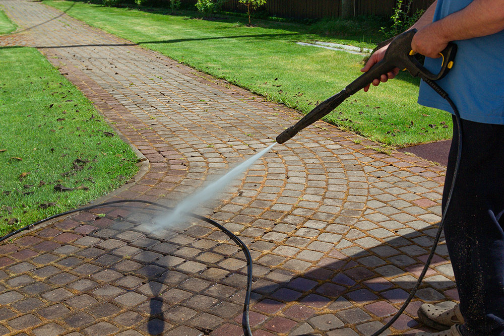 Cleaning street with high pressure power washer, washing stone g
